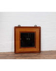 Two-toned elm and rattan square mirror with beveled glass, vintage 1950s Chinese style, against white brick wall.