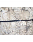 Close-up of white stone Bodhisattva sculpture with intricate carved robes and black strap, vintage Chinese style.