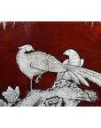 Close-up of a dark red lacquered dowry box with hand painted silver-engraved birds and flowers.