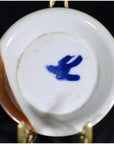 Close-up of vintage Chinese porcelain dish with brown rim and blue bird mark visible on the underside.