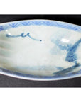 Blue and white porcelain dish with hand painted blue designs and geometric border, vintage style, close-up view.