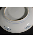 Close-up of underside of vintage Chinese porcelain plate with small blue decorative patterns near base.