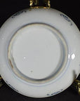 Close-up of the underside of a white porcelain vintage Chinese plate on a brass stand with dark background.