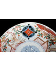 Close-up of a vintage Chinese porcelain plate with vibrant red, green, and blue hand-painted floral patterns.