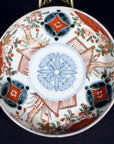 Close-up of a vintage Chinese porcelain plate with red, green, and orange floral and geometric designs on white.