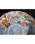 Close-up of a vintage Chinese porcelain plate with red, blue, and green hand-painted geometric and floral designs.