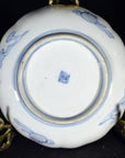 White and blue porcelain plate bottom with square mark, displayed on a gold stand.