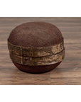 Brown rattan circular hat box with weathered patina on a wooden floor indoors.