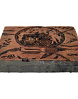 Close-up of vintage copper Batek ink block stamp with carved designs and Cyrillic text, used for printing or stamping.