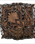 Close-up of vintage copper ink block with black and gold peacock and floral motifs, textured square design.