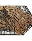 Close-up of vintage copper batik ink block with intricate golden-brown pattern on black lattice background.
