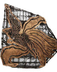 Close-up of a vintage copper Batek ink block with intricate patterns on a wire mesh background.