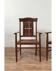 Brown wood Dutch Colonial armchair with pierced slats and bonnet rail on a wooden floor indoors.