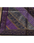 Purple silk fabric with silver and gold embroidery on a wooden surface.