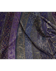 Close-up of purple silk fabric with silver and gold embroidery, showing intricate designs.