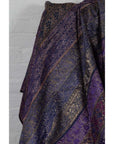Purple silk fabric with purple, silver, and gold embroidery, displayed against a light-colored wall.