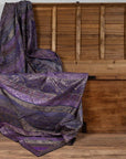 Purple silk fabric with silver and gold embroidery draped over a wooden chest on the floor.