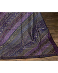 Purple silk fabric with purple, silver, and gold embroidery on a wooden floor.