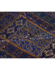 Purple silk fabric with embroidered floral and geometric designs in purple, silver, and gold tones, close-up.