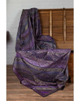 Purple silk fabric with gold and silver embroidery draped over a wooden chest.