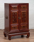 Red Negora lacquer and gilt calligraphy Japanese display cabinet against a white wall indoors.