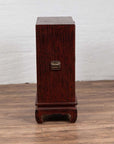 Red lacquer and wood Japanese display cabinet with gilded calligraphy on wood floor indoors.