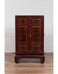 Red Negora lacquer and wood Japanese display cabinet with gilded calligraphy on a wooden floor by a white wall.