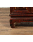 Close-up of red lacquer and gold calligraphy leg on vintage Japanese display cabinet indoors.