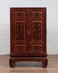 Red Negora lacquer cabinet with gilded calligraphy, short curved-leg base, shown indoors.