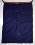 Dark blue wax-printed cotton apron with front pocket and striped orange-brown strap, close-up view.