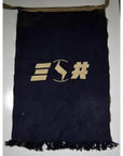 Black fabric apron with fringed edges and a tan geometric design at the center, close-up.