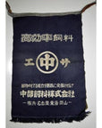 Navy blue wax printed cotton apron with white Japanese text, symbols, and decorative fringe at the bottom.