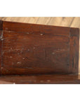 Close-up of brown wood staircase tansu cabinet with four drawers, Japanese style, set against wood paneling indoors.