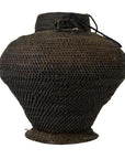 Close-up of dark brown rattan woven farmer's basket from the Philippines with a wide bottom, narrow neck, black string near top.