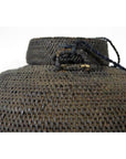 Close-up of a brown woven farmer's basket from the Philippines with handle and dark cord, on white background.