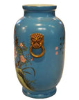 White porcelain vase with hand-painted flowers, birds, gold lion ring handles, and Chinese calligraphy, close-up.