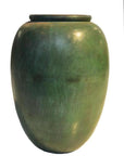 Close-up of vintage green bronze urn with large smooth body and narrow flared rim, used as subtle decor.