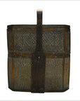 Brown rattan basket with tall central handle and intricate woven patterns, close-up view.