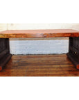 Light wood waterfall table with curved edges on wooden floor, white brick wall background.