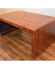 Brown wood waterfall coffee table with rustic Chinese antique style on wooden floor against white brick wall.