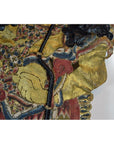 Close-up of yellow-hand Wayang Kulit shadow puppet made from Balinese cowhide, holding black stick on white background.
