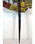 Close-up of tan cowhide Wayang Kulit Balinese shadow puppet held by a gloved hand with a pointed wooden staff.