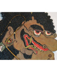 Close-up of an antique brown cowhide Wayang Kulit Balinese shadow puppet with curly hair and bold facial features.