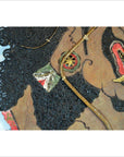 Close-up of antique Balinese Wayang Kulit shadow puppet with textured hair and detailed features, made from cowhide.