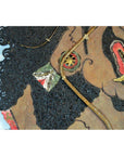 Close-up of antique Balinese Wayang Kulit shadow puppet with textured hair and detailed features, made from cowhide.