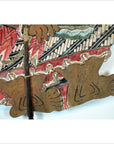 Close-up of colorful cowhide Wayang Kulit Balinese shadow puppet feet in a zigzag garment.