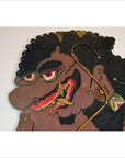 Brown cowhide shadow puppet with curly hair, large red eyes, and ornate earrings, Balinese Wayang Kulit style.