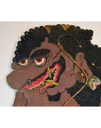 Brown cowhide shadow puppet with curly hair, large red eyes, and ornate earrings, Balinese Wayang Kulit style.