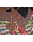 Close-up of brown cowhide arm and hand of Balinese Wayang Kulit shadow puppet with patterned garment.