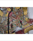 Balinese cowhide wayang kulit shadow puppet with ornate patterns and dragon-shaped foot on white background.